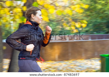 Motion blurred young attractive woman running in forest