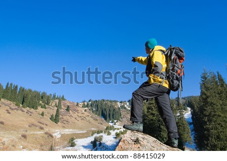 Climbing young adult at the top of summit with aerial view of blue sky and mountain