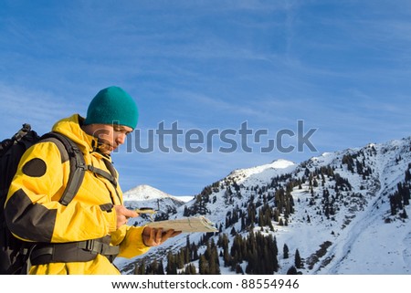 Climbing young adult with map and compass. Aerial view of mountain and blue sky