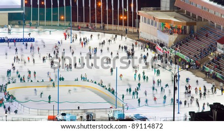 Huge ice skating rink with motion blurred large group of skating people. Kazakhstan, Medeo is an outdoor speed skating and bandy rink, located in a mountain valley