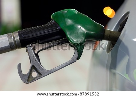 A close-up of a petrol pump while get petrol in a car