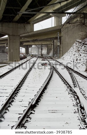 snow covered train tracks run underneath a bridge