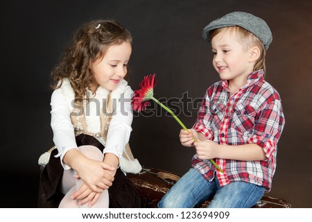 Little boy giving a red flower to a beautiful smiling little girl. Valentine day