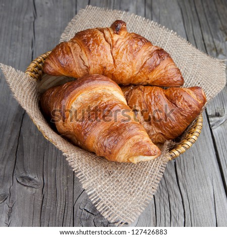 Crispy fresh croissants in a basket on a wooden table