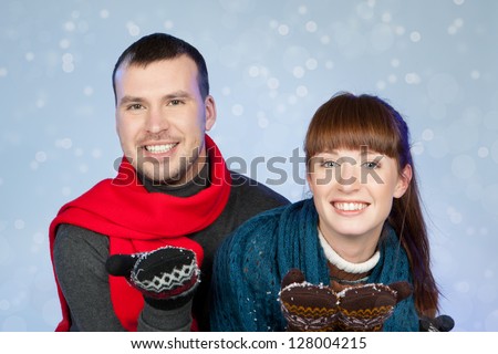 Portrait of romantic young couple in winter clothing over blue