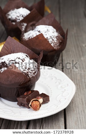 Homemade chocolate muffins with powder sugar on dark wooden background