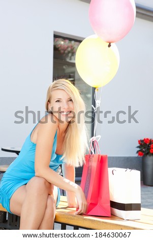 Lovely young happy woman with shopping bags and balloons outdoors