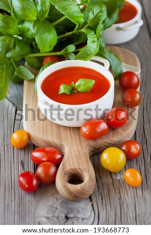 Traditional tomato soup with basil on dark wooden background, selective focus