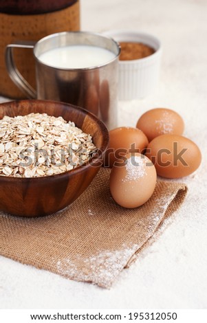 Baking ingredients - milk, eggs and oatmeal on kitchen table, selective focus