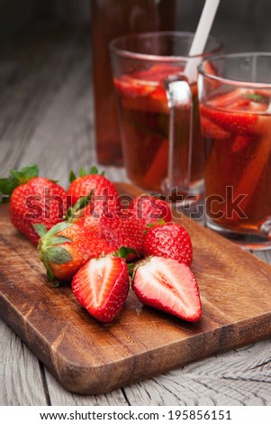 Cold strawberry drink with fresh strawberries and mint on a dark wooden background