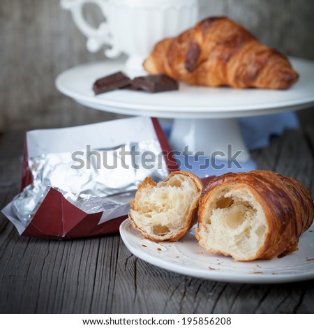 Morning breakfast with fresh croissants and cup of tea on dark wooden background, selective focus