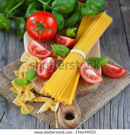 Spaghetti and tomatoes with herbs on a dark and vintage wooden background, selective focus