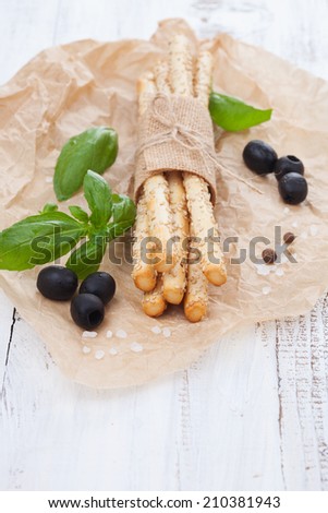 Grissini bread sticks with sesame, sea salt and basil on white wooden background