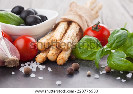 Grissini bread sticks with sesame, sea salt and basil on old wooden background