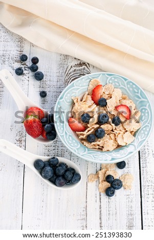 Morning breakfast with cornflakes and fresh berries on white wooden table