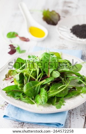 Fresh green salad with spinach, arugula, romaine and lettuce and sesame seeds on a rustic white background, selective focus