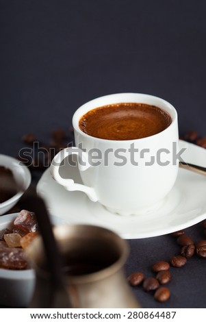 Cup of coffee, brown sugar and roasted beans on dark background, selective focus