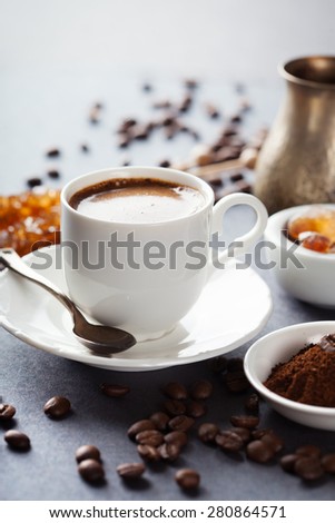 Cup of coffee, brown sugar and roasted beans on dark background, selective focus