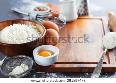 Ingredients and tools for baking - flour, eggs, sugar and rolling pin on the black background, selective focus