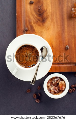 Cup of coffee, brown sugar and roasted beans on dark background, top view