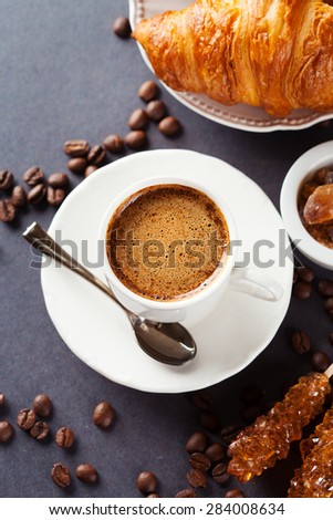 Crispy fresh croissants and cup of coffee on a black background, morning breakfast, top view