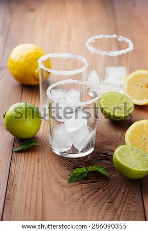 Ingredients for lemonade - fresh lemons, limes and mint on rustic wooden background, selective focus