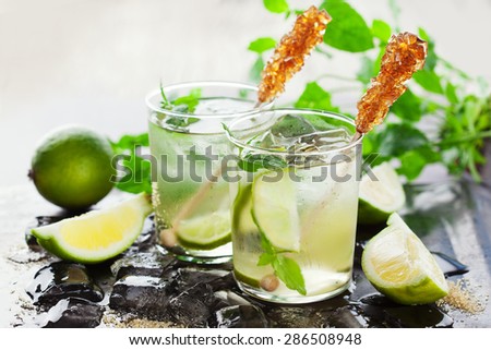 Healthy organic lemonade with fresh lemon, lime and mint on black background, selective focus