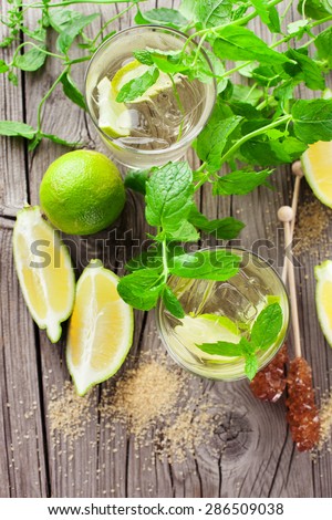 Healthy organic lemonade with fresh lemon, lime and mint on rustic wooden background, top view