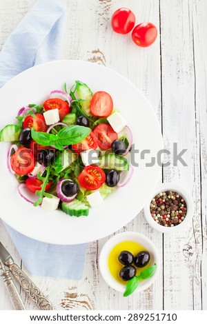 Greek salad with feta cheese, fresh vegetables and olives on rustic white wooden background, top view