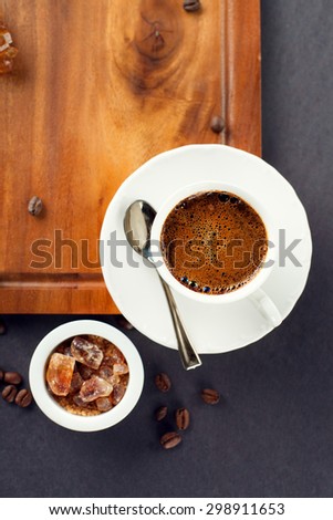 Cup of coffee, brown sugar and roasted beans on dark background, top view
