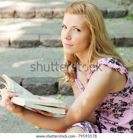 Beautiful young blonde woman reading a book on the nature