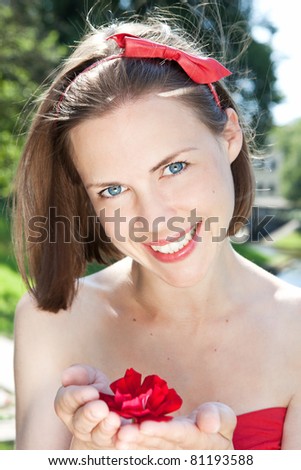 Portrait of young beautiful smiling female with flower in the park