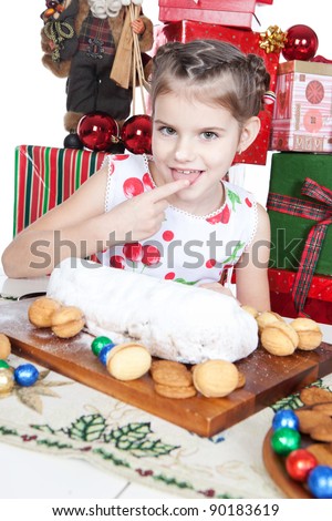 Cute little girl eating Christmas cake with powdered sugar at a table