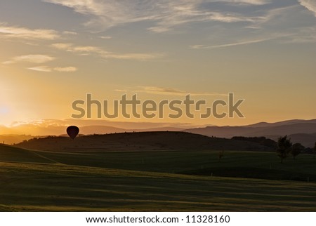 A hot air balloon landing on a golf course at sunset