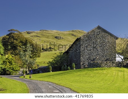 Scenic view of stone barn conversion in countryside with hills in background, Cumbria, England.