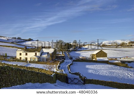 Scenic view of farm and lane in snow covered countryside, Cumbria, England.