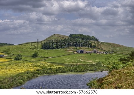 A view from Hadrian\'s wall looking across Crag Lough to a farm on a hill