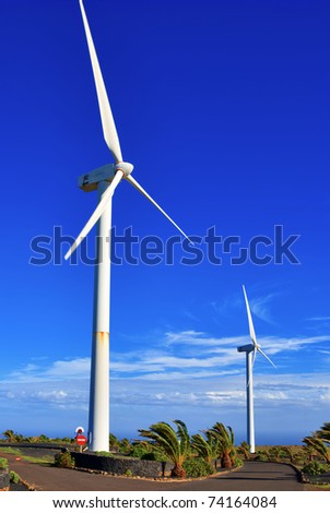 Scenic view of two wind turbines with blue sky and cloudscape background on island on Lanzarote, Canary Islands, Spain.