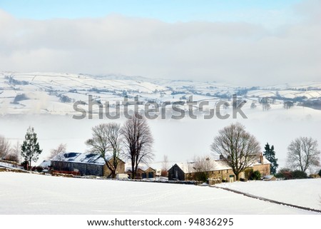 Remote stone farm buildings blanketed in heavy snow and mist in a frozen winter landscape.