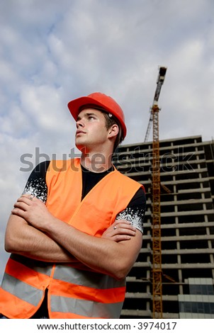 Construction supervisor in safety helmet and reflex vest in front of construction site.