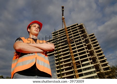 Construction supervisor in safety helmet and reflex vest in front of construction site.
