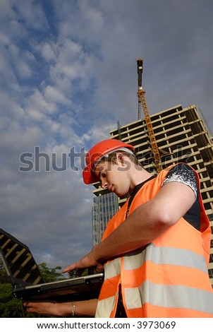 Construction supervisor in safety helmet and reflex vest with notebook in front of construction site.