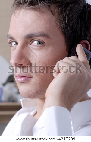 A portrait of a handsome young man having a conversation on his cellphone. Vertical perspective with white background.