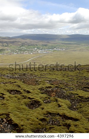 Icelandic landscape - moss on lava field in front and village in valley in background Iceland nature.