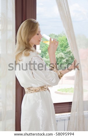 Woman drinking juice at the open window at the morning