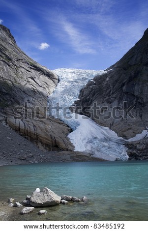 Melting Glacier over the blue mountain lake. Norway.