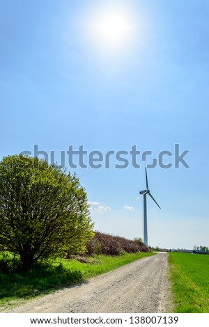 Wind turbine against blue sky. Wind power is the conversion of wind energy into a useful form of energy, such as using wind turbines to make electrical power. Here a road is leading towards one.