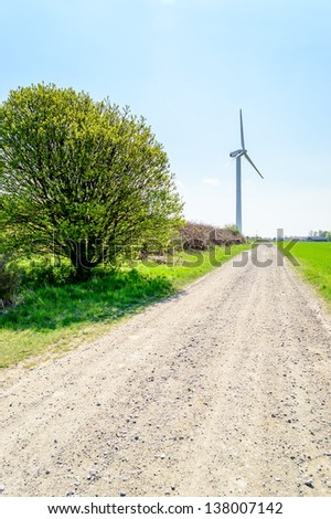 Wind turbine against blue sky. Wind power is the conversion of wind energy into a useful form of energy, such as using wind turbines to make electrical power. Here a road is leading towards one.