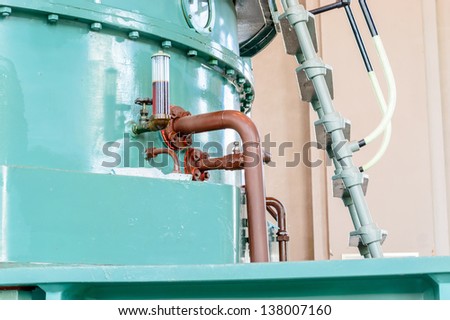 A large generator at a hydro electric power plant. Casing is bluish green. Generator in center of large building.