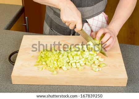 Male hands chopping celery on wooden cutting board